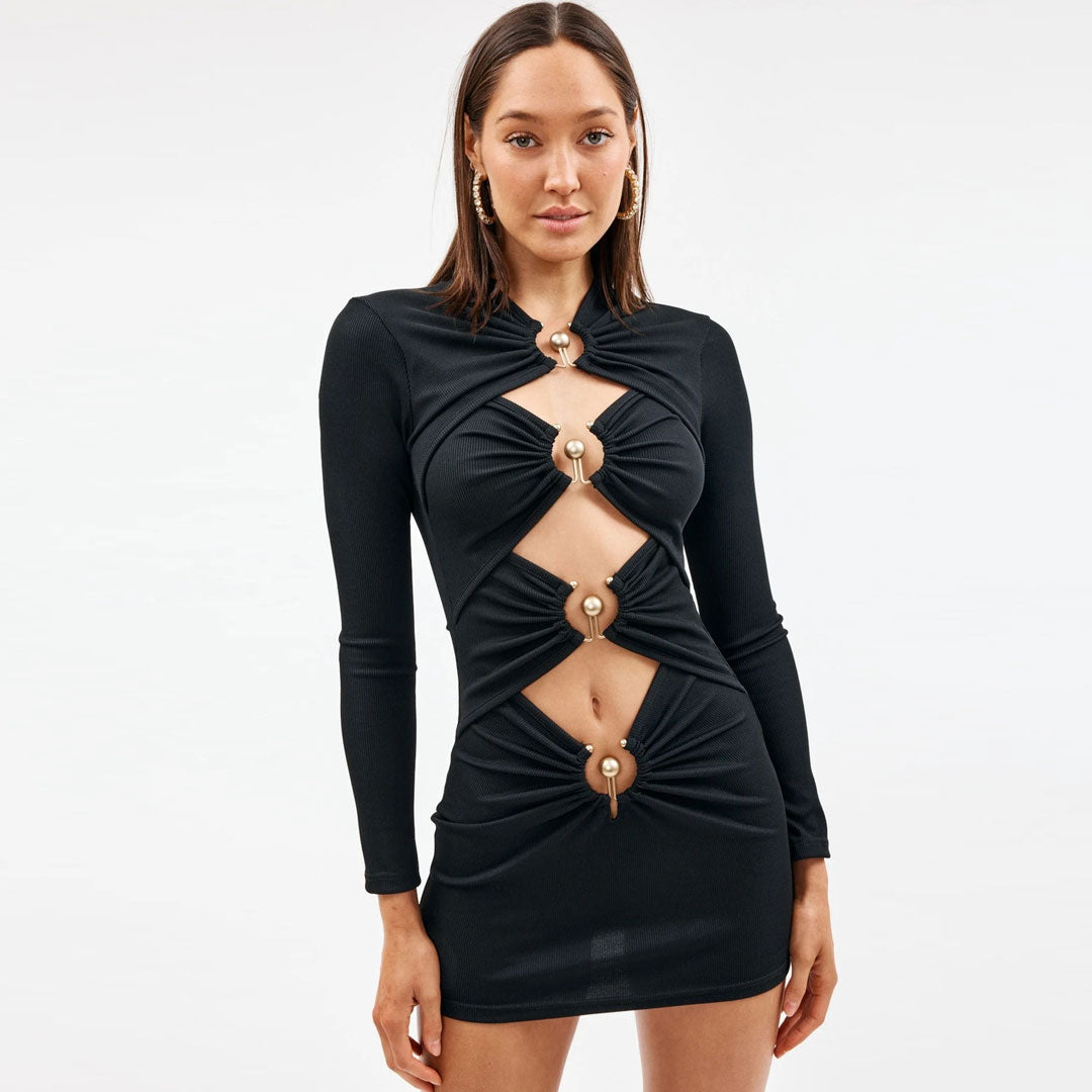 Model wearing a black long-sleeve mini dress with cut-outs and gold hardware