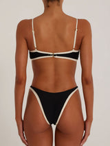 woman wearing a black and cream bikini set, back view