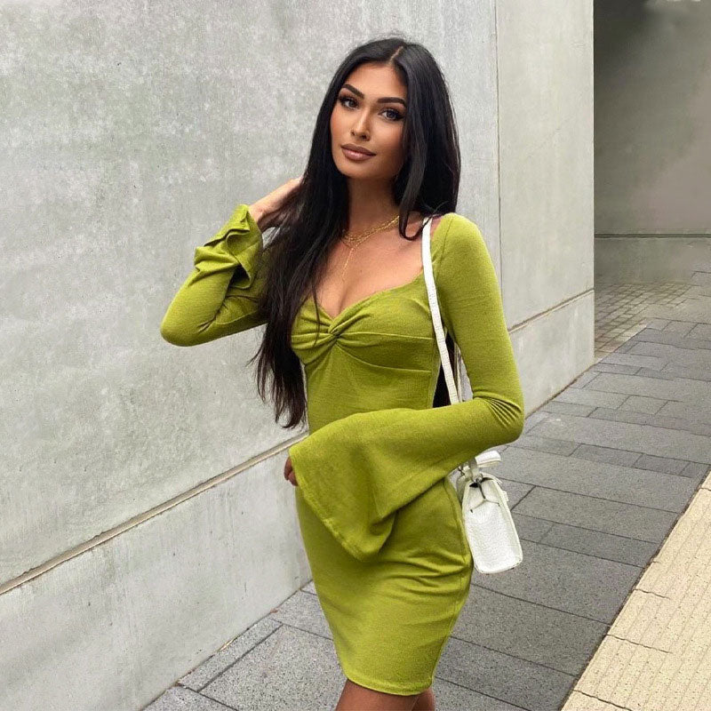 Woman wearing a lime green long-sleeved mini dress with a twisted front and flared sleeves, posing outdoors