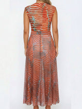 Back view of a woman wearing a sheer, orange and blue printed maxi dress.