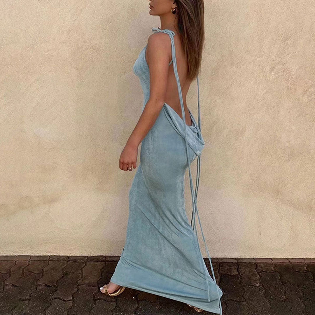 Woman walking from the side in a light blue sleeveless maxi dress with a draped back and adjustable tie straps.