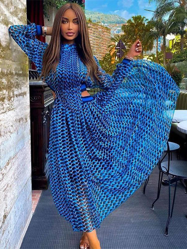 Woman wearing a flowing blue and black geometric print midi dress with long sleeves and cut-out details.