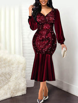Woman wearing a red sequined midi dress with long puff sleeves and a mermaid hemline.