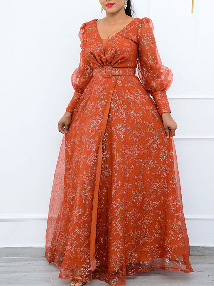 Woman wearing a long orange floral print gown with sheer puff sleeves, a V-neckline, and a belted waist.