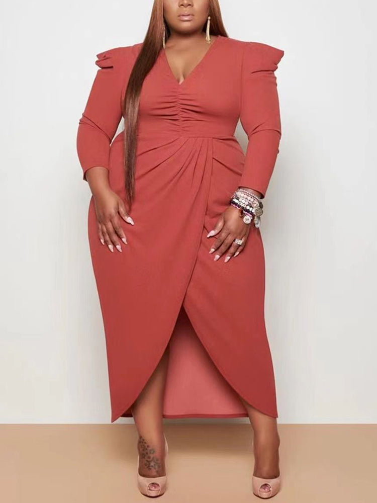 Plus-size woman wearing a rust-colored long-sleeved V-neck ruched wrap dress with puff sleeves and a high slit, standing against a neutral background.