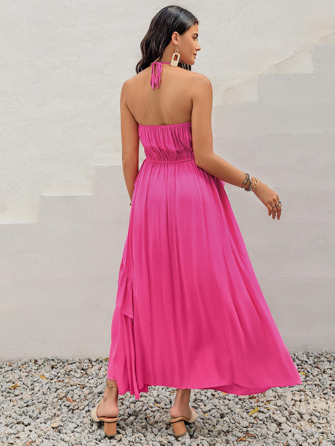 Back view of a woman wearing a pink tiered maxi dress with a halter neck and ruffle trim.