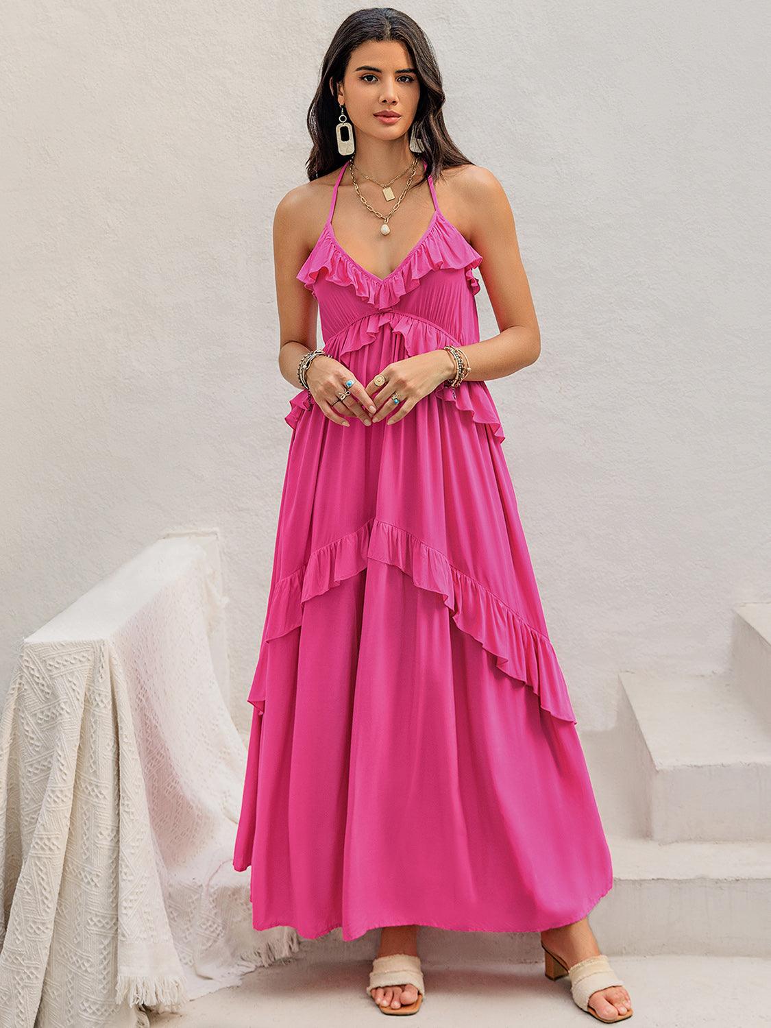 Full-body shot of a woman wearing a pink tiered maxi dress with ruffle trim and a v-neckline, posing outdoors.