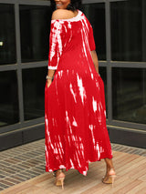 Back view of a woman wearing a red tie-dye maxi dress with an asymmetrical hem and pockets.