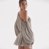 Back view of a woman in a grey chiffon mini dress, showcasing the open back and draped sleeves.