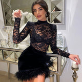 Woman wearing a black lace and velvet mini dress with feather trim, posing by a mirrored console table.