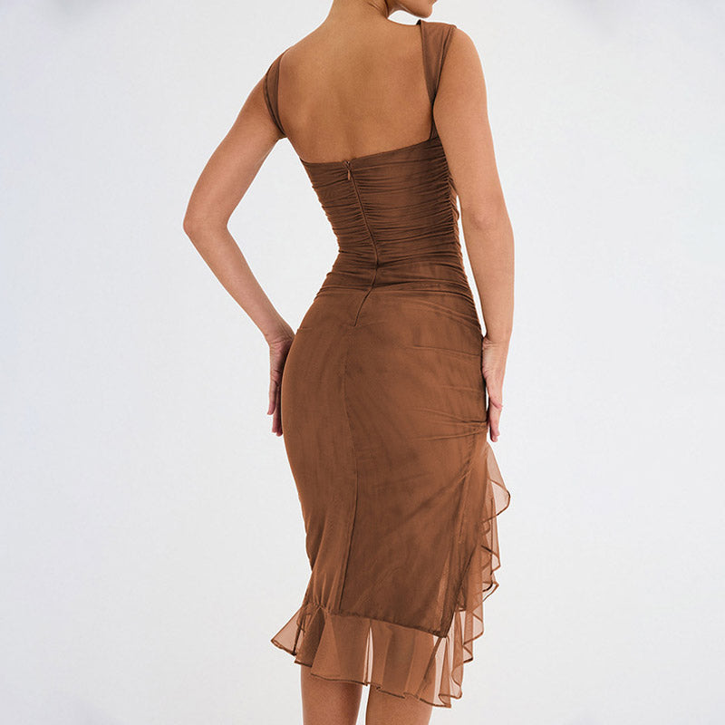 Woman wearing a brown sheer mesh ruched dress with a ruffled asymmetrical hemline, posing from the back.