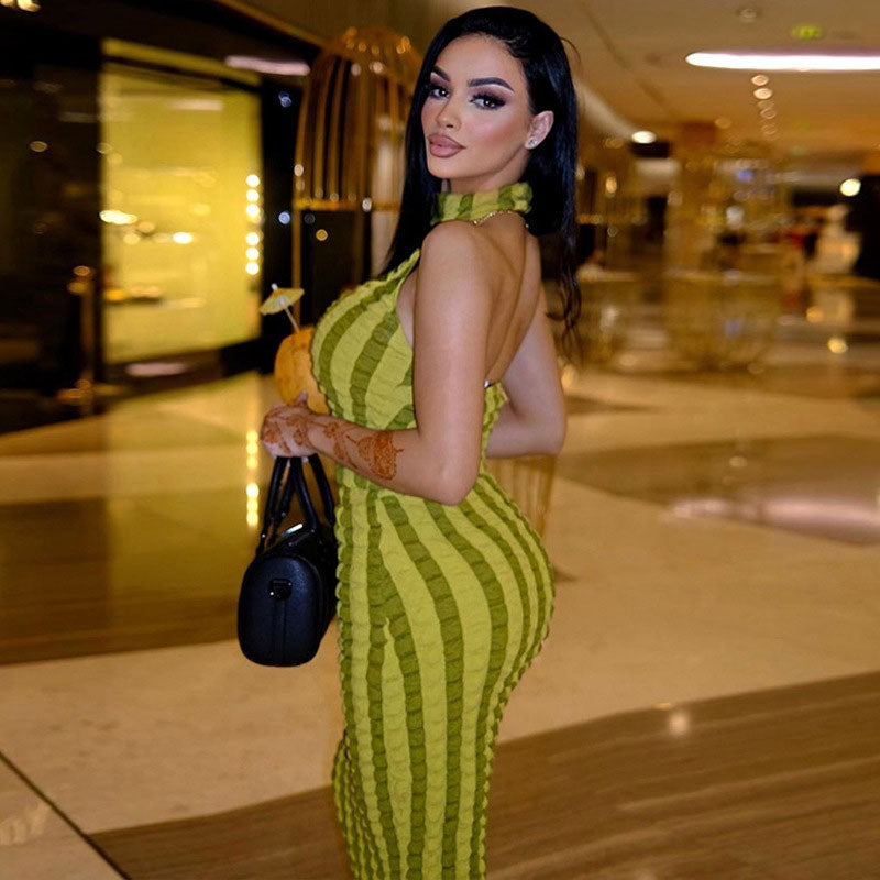 Side profile of a woman in a ruched lime green striped maxi dress, showcasing the back detail and the textured fabric.