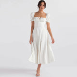 Woman wearing a white midi dress with puff sleeves and a square neckline.
