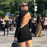 woman in a black long-sleeve open-back mini dress with cut-out details