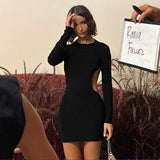 woman in a black long-sleeve dress with side cut-outs posing near foliage