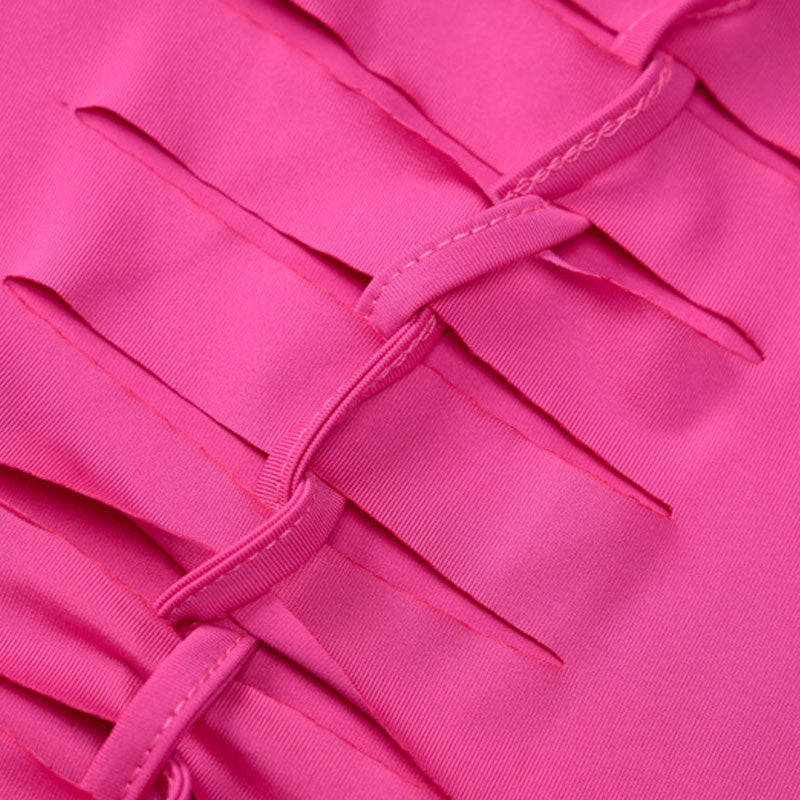 Close-up of the fabric of a pink dress, showing intricate cut-out and ribbon detailing.