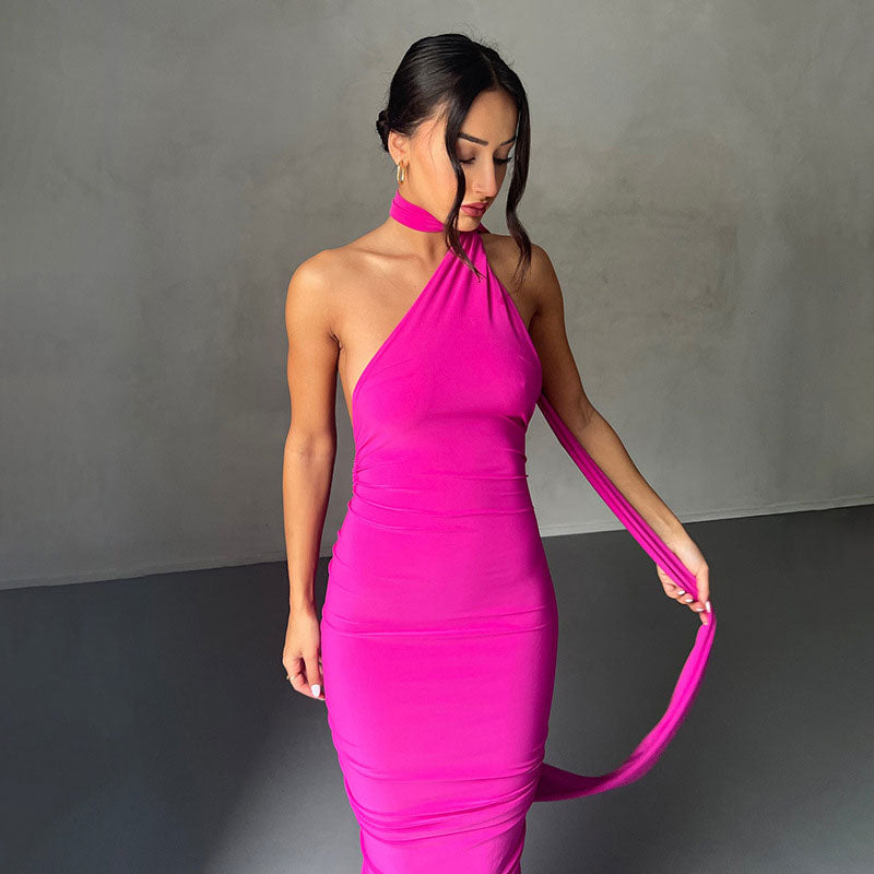 Woman wearing a fuchsia halter neck gown with a long trailing scarf.