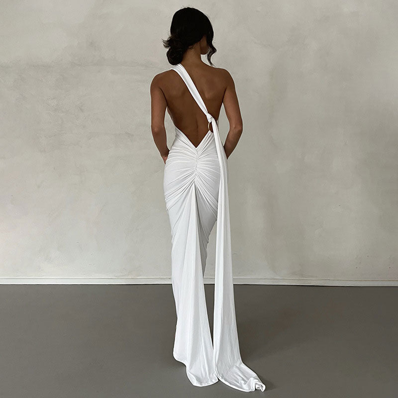 Rear view of a woman in a white floor-length gown with a low back and draped train.