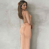 woman wearing a peach velvet maxi dress with a halter neckline and open back