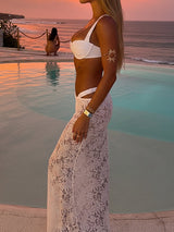 side view of woman in white bikini and lace maxi skirt by pool