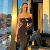 Woman wearing a black midi dress with sheer side panels and cut-out bust detail, holding a glass and purse.