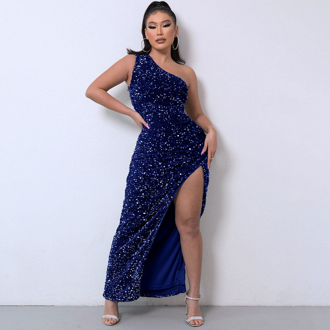 Woman wearing a navy blue sequined one-shoulder maxi dress with a high slit.