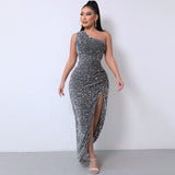 Woman wearing a shimmering grey one-shoulder sequined gown with a high slit.