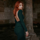 woman wearing a long-sleeved, green, sparkly, fitted midi dress from the back, showing a low back detail