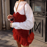 Close-up of a woman in a red sparkly mini dress and white button-down shirt, holding a bottle of soda.