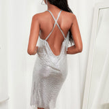Back view of a woman in a silver sequined halter dress, highlighting the open back design.