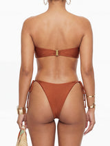 Back view of a woman in a strapless brown bikini with gold hardware