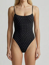 Woman wearing a black one-piece swimsuit with a polka dot embellishment, front view.