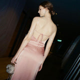 Back view of a woman in a pink satin slip dress with an open back and tie closure