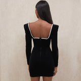Back view of a woman in a black velvet mini dress with a square neckline and zipper closure