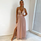 Full length shot of a woman wearing a blush pink formal dress with a sequined bodice and a high slit.