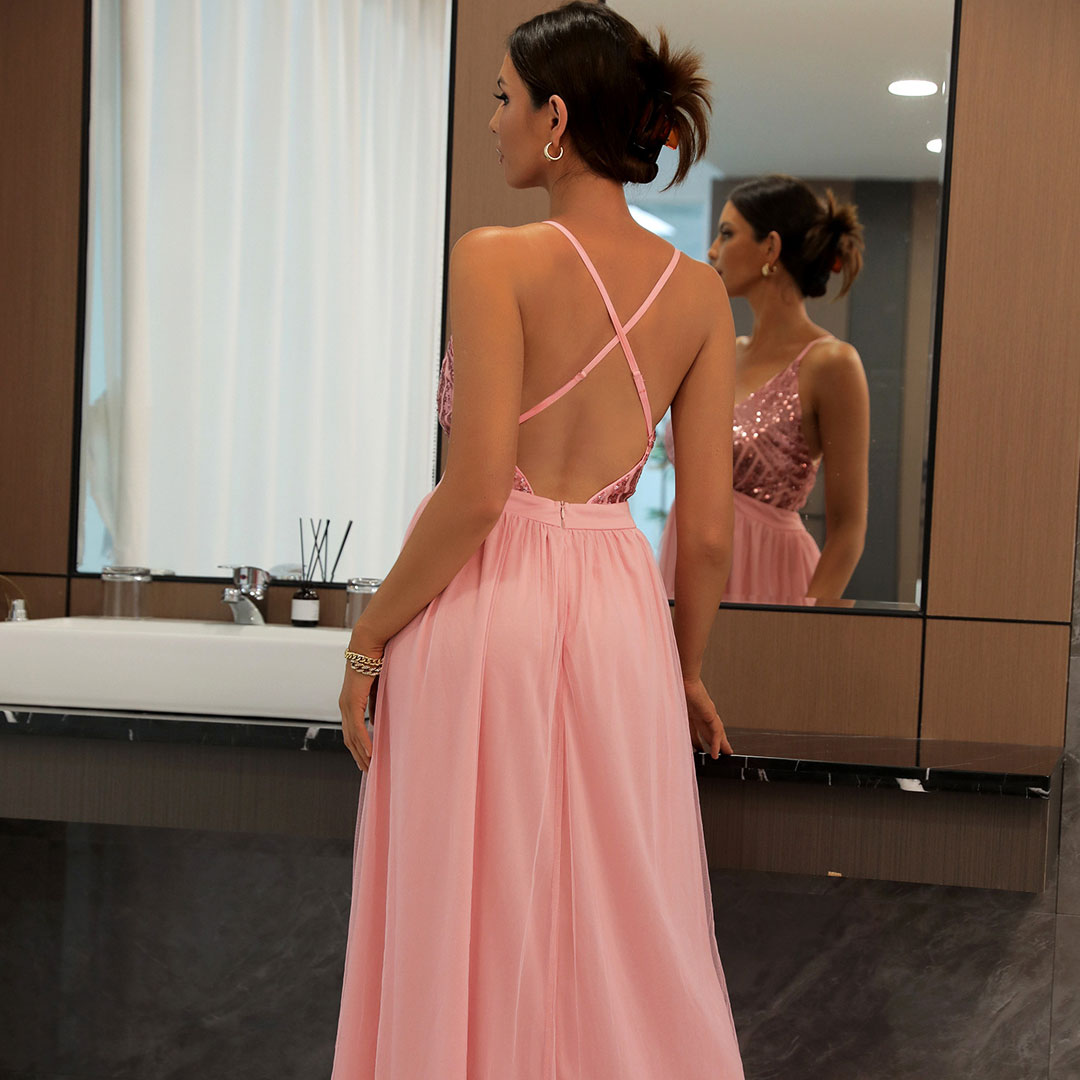 Back view of a woman in a pink sequined and chiffon evening gown with spaghetti straps and an open back.