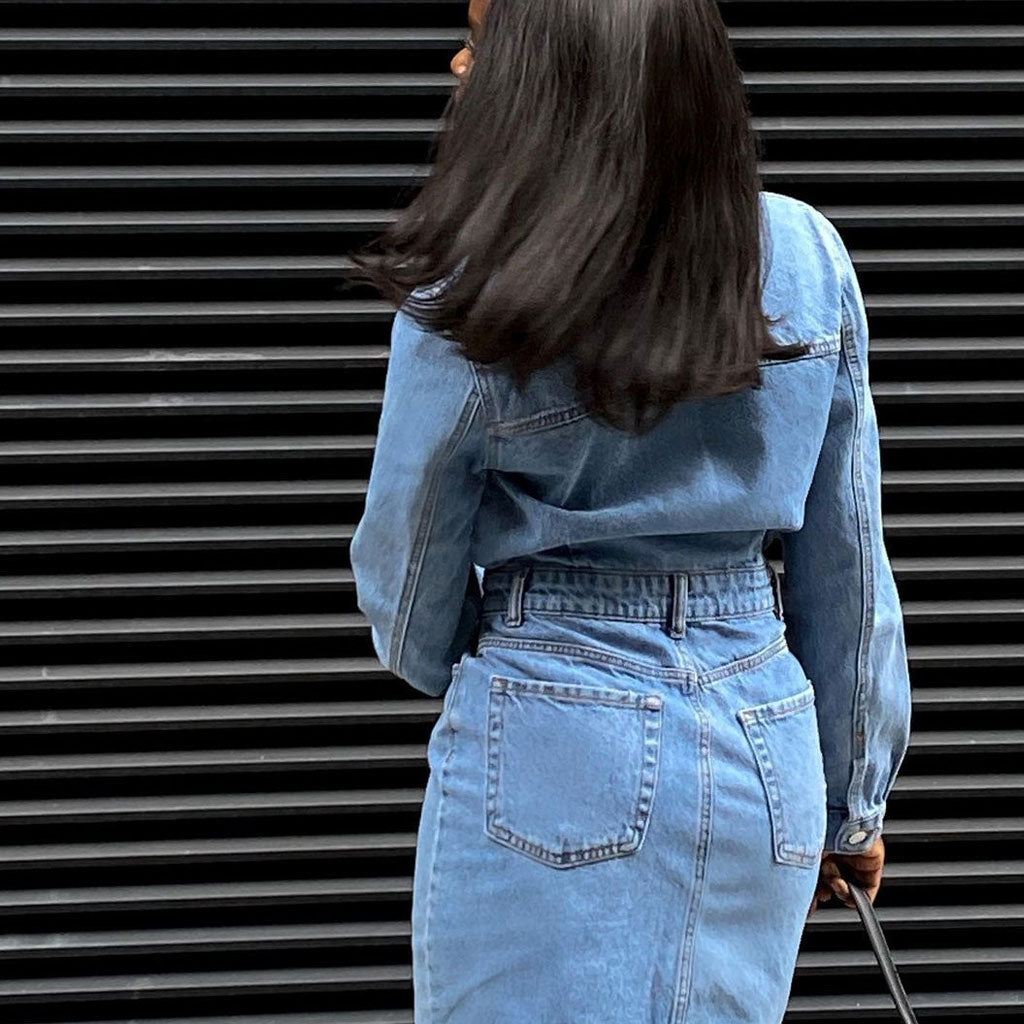 Back view of a woman wearing a blue denim shirt dress.