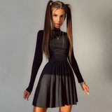 Woman wearing a black long-sleeved ribbed knit dress with a mock neck and a fit and flare skirt, standing in front of a light gray background.