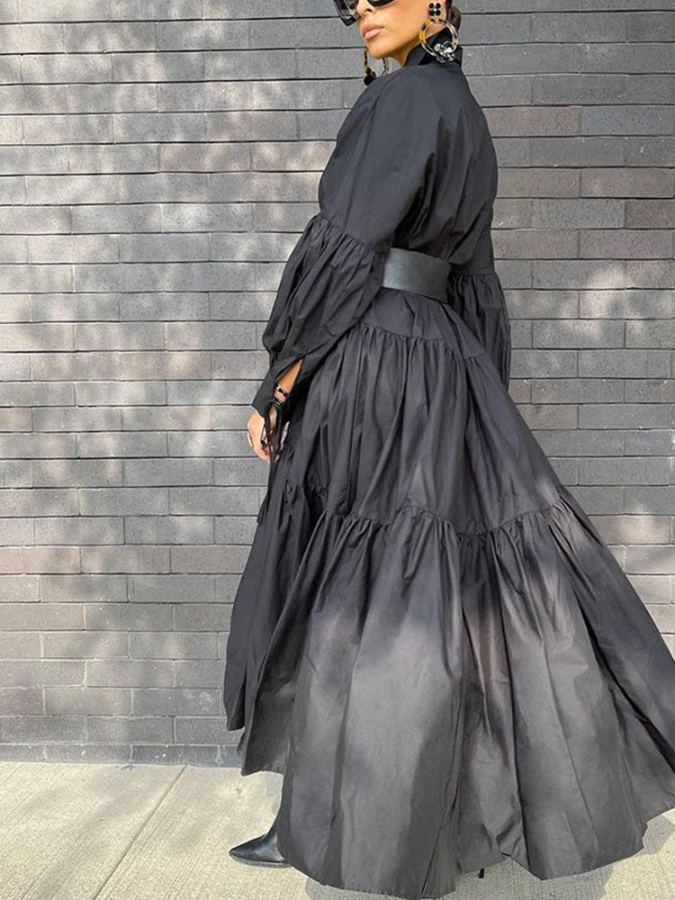 Back view of a woman wearing a black tiered maxi dress with balloon sleeves, walking outdoors.