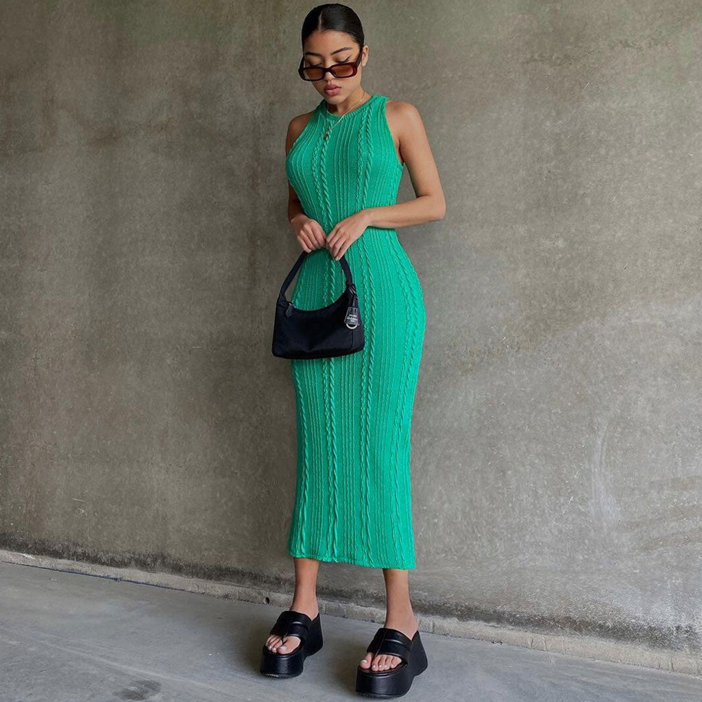 Woman wearing a green sleeveless midi dress with a ribbed texture and cable knit detailing, black platform sandals, and sunglasses.