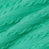 Close-up of the green knit fabric of the dress, showing the ribbed texture and cable knit detailing.