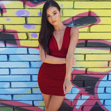 Woman wearing a red ruched bodycon dress with a deep V-neckline, standing in front of a graffiti wall.