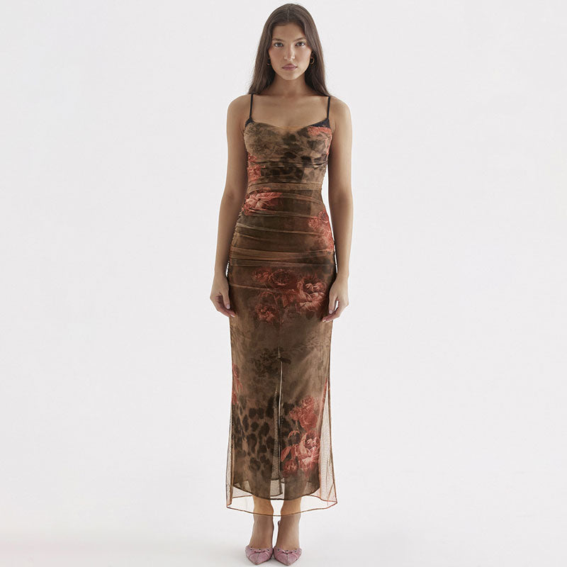 Woman wearing a long, brown, sheer mesh dress with a floral and animal print, featuring spaghetti straps and a thigh-high slit.