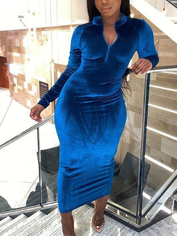 A woman poses on stairs wearing a royal blue velvet midi dress with a quarter-zip neckline.