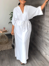 Full-length view of a woman in a white maxi dress with flowing sleeves.
