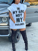 Woman wearing a white hooded mini dress with a graphic print, paired with black knee-high boots, standing next to a vehicle.