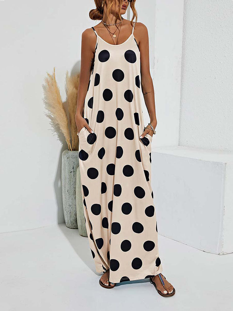 Woman wearing a beige polka dot maxi dress with spaghetti straps and pockets, standing in a room with decor, slightly angled front view