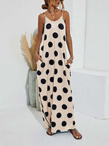 Woman wearing a beige polka dot maxi dress with spaghetti straps and pockets, standing in a room with decor, slightly angled front view